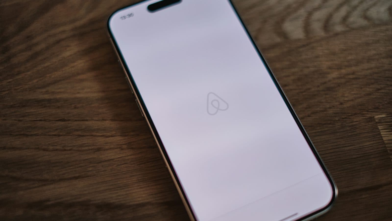 Celular com o aplicativo do Airbnb aberto sobre uma mesa de madeira