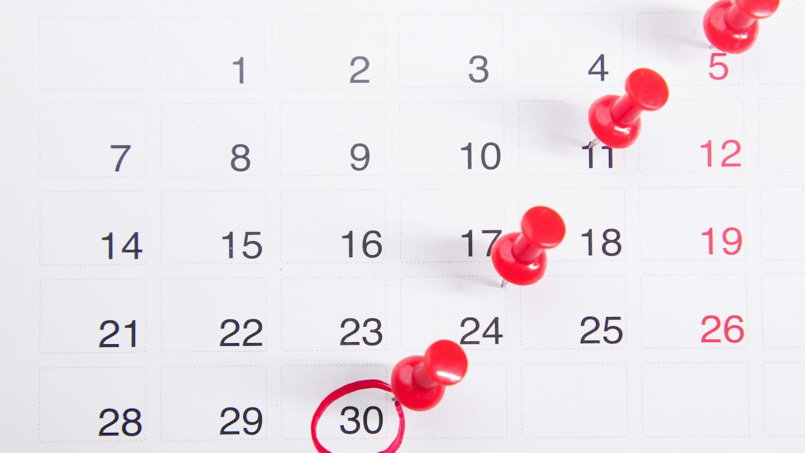 Calendário com alfinetes vermelhos marcando datas